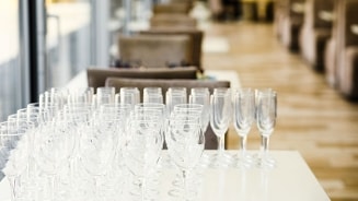 Een rij schone wijnglazen en champagneglazen op een witte tafel in een restaurantinterieur