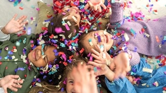Vrolijke kinderen die samen liggen en bedekt zijn met gekleurde confetti