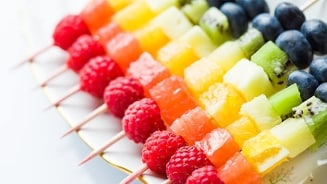 Fruitspiesjes met frambozen, grapefruit, ananas, kiwi en bosbessen op een bord