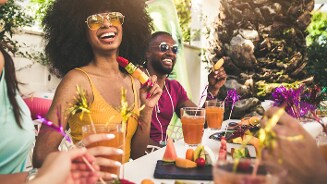 Vriendengroep geniet samen buiten van verkoelende drankjes en fruitspiesjes aan een zomerse tafel