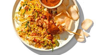 Gebakken rijst met kipspies en pindasaus, geserveerd met kroepoek.