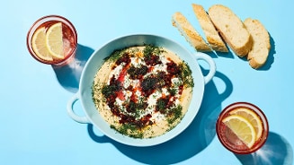 Gerecht met hummus, kruiden en pitabroodjes geserveerd met drankjes gegarneerd met schijfjes citroen.