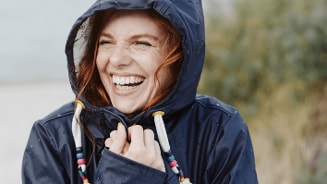 Persoon in een regenjas met kleurrijke koorden, gezicht is wazig gemaakt.