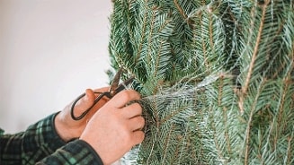 Handen knippen het net van een kerstboom los
