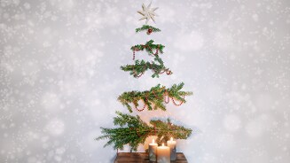 Gedompte kerstboom decoratie met kaarsen en een ster bovenaan.