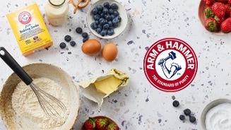 Arm & Hammer baking soda, ingrediënten zoals bloem, boter, eieren, blauwe bessen, aardbeien en melk, op een keukenblad, klaar voor het bakken.