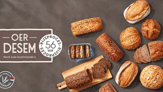 Verschillende soorten oerdesem brood op een tafel, met een bordje waarop staat '56 uur rijstproces' en het label 'Met tarwe uit Nederland'.