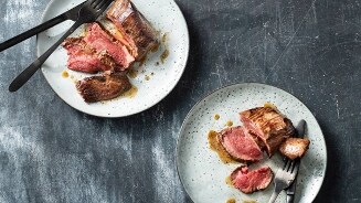 Gegrilde biefstuk geserveerd op twee borden met vork en mes.