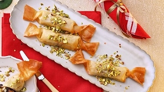 Dessert van filodeeg gevuld met pistachenoten, gepresenteerd op een schaal.