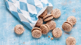 Macarons in een blauw-witte papieren zak op een blauwe achtergrond.