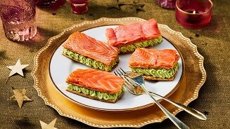 Goudkleurige schaal met zalmhapjes op een feestelijke tafel.