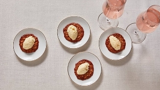 Kleine borden met een zoet gerecht en twee glazen rosé op een licht tafellaken.