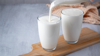 Twee glazen melk, één wordt ingeschonken.