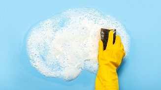 Schoonmaken met zeep en een spons, met een gele handschoen