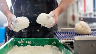 Bakker met deegbollen in handen in een bakkerijomgeving