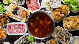 Rijke selectie van verse ingrediënten en een hete pan met soep, geschikt voor een Aziatisch fondue- of hotpotmaaltijd.