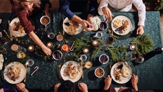 Feestelijk gedekte tafel met gerechten, kaarsen en kerstdecoraties.