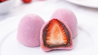 Roze mochi met aardbei en chocoladevulling, gepresenteerd op een bord.