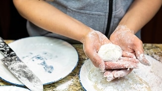 Persoon maakt deegbal in een keuken
