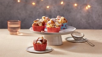 Muffins met een feestelijke presentatie op een schaal, omgeven door lichtjes.