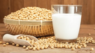 Glas sojamelk met een mand vol sojabonen op een houten tafel