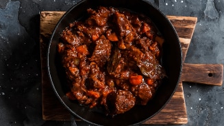 Stoofschotel met rundvlees en groenten in een gietijzeren pan.