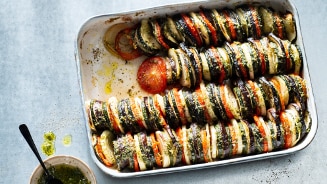 Kleurrijke ratatouille schotel in een ovenschaal met een kommetje pestodressing ernaast.