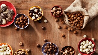 Diverse variëteiten chocolade en kruidnoten op houten tafel.