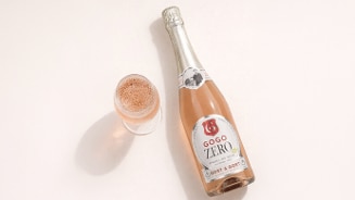 Fles GOGO ZERO Sparkling Rosé van het merk Gort & Gort naast een glas met mousserende rosé.