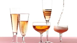 Alcoholvrije bubbels in verschillende glazen op een rij op een roze ondergrond.