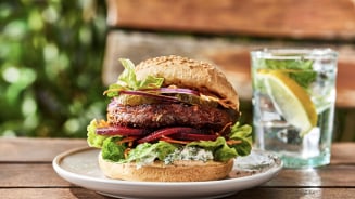 Vegan burger met groenten en een glas water met citroen en munt op de achtergrond.