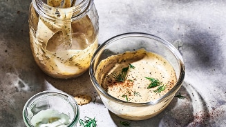 Zelfgemaakte mosterddressing in een glazen pot en kom, gegarneerd met verse dille.