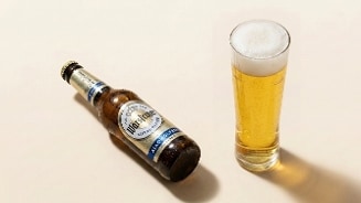Fles Warsteiner Alkoholfrei pilsener naast een glas met ingeschonken alcoholvrij bier.