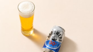 Glas met alcoholvrij Brouwers bier naast een blikje Brouwers 0.0% alcoholvrij bier.