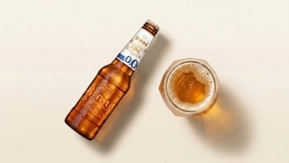 Fles Brand IPA 0.0 alcoholvrij bier naast een glas met bier op een lichte ondergrond.