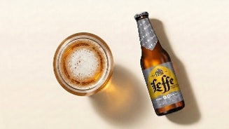 Glas blond alcoholvrij Leffe bier naast een flesje Leffe Blond 0.0%