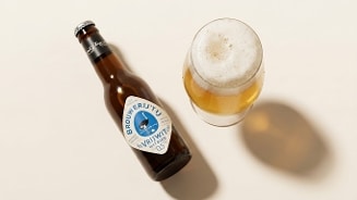 Fles Brouwerij 't IJ Vrijwit witbier en een glas gevuld met witbier op een lichte achtergrond