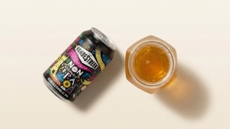 Blikje Vandestreek Playground Non-Alcoholic IPA naast een gevuld glas bier op een lichte ondergrond.