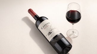 Fles Catena Malbec rode wijn en gevuld wijnglas op een lichte ondergrond