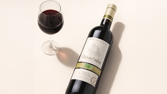 Fles Château Coulon rode wijn en een glas rode wijn op een lichte ondergrond