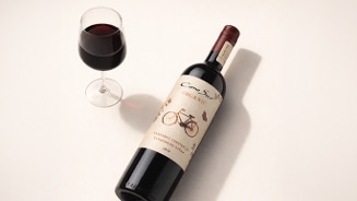 Fles Cono Sur Organic Cabernet Sauvignon Carmenere wijn met een glas rode wijn ernaast op een lichte ondergrond