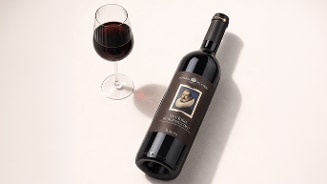 Fles rode wijn Fattoria del Cerro Vino Nobile di Montepulciano met een gevuld wijnglas op een lichte ondergrond.