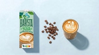Pak AH Terra Barista Soja naast een glas koffie met latte art en enkele koffiebonen.