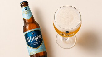 Fles Affligem Belgisch Wit abdijbier en bijpassend glas met geschonken bier en schuimkraag.