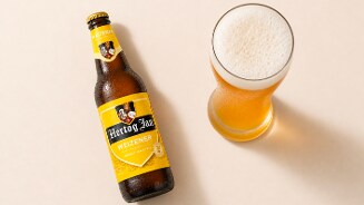 Fles Hertog Jan Weizener bier naast een gevuld bierglas met schuimkraag.