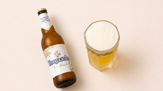 Fles Hoegaarden Witbier en een glas gevuld met Hoegaarden witbier met schuimkraag op een lichte ondergrond.