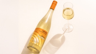Fles Moscato witte wijn van het merk Verano, met daarnaast een gevuld glas witte wijn.