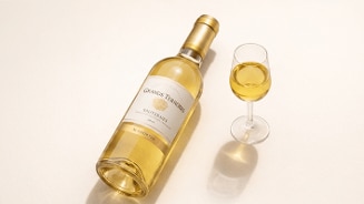Fles Grands Terroirs Sauternes dessertwijn met gevuld wijnglas op een lichte ondergrond