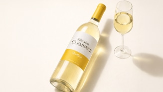 Fles Sélection Clémence Moelleux witte wijn naast een gevuld wijnglas op een lichte achtergrond.
