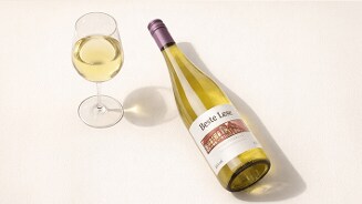 Fles witte wijn Beste Lese met een gevuld wijnglas op een lichte ondergrond